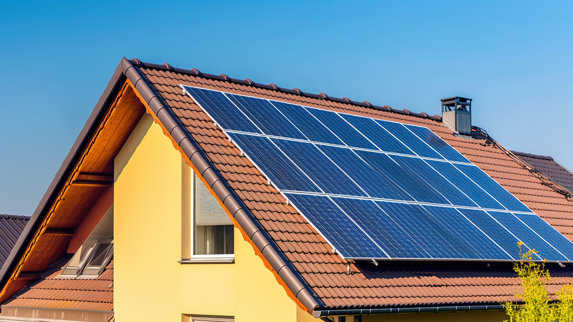 Casa com telhas aparentes no telhado e com placas de energia solar instaladas, um céu azul.